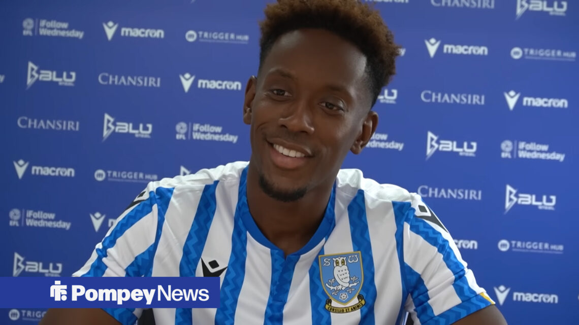Jamal Lowe in Sheffield Wednesday home shirt with advertising hoardings behind him.