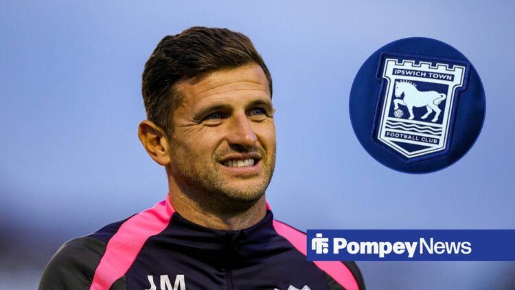 John Mousinho smiling at Ipswich badge in circle