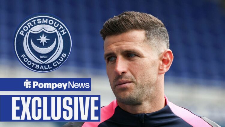 John Mousinho looking at Portsmouth badge in circle